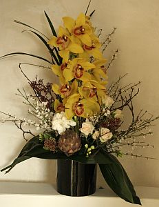 Corporate arrangement made of cymbidium orchids, white roses, freesia, skimmia and genista